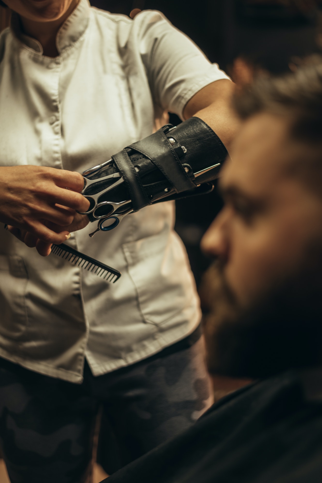 Professional barber wearing her tools on the forearm and working in her barbershop