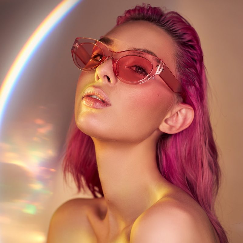 Sexy Woman with creative hair coloring in pink red, girl in sunglasses. Beautiful smile